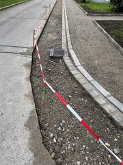 Fototapeta premium Road with a red and white striped barrier and a drainage grate