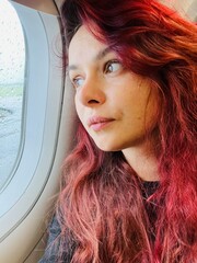 Young woman gazes thoughtfully out airplane window during rainy flight, embracing travel anticipation