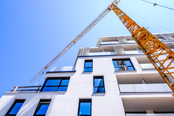 Construction crane reaches to the sky during a sunny afternoon in an urban area with bright blue skies