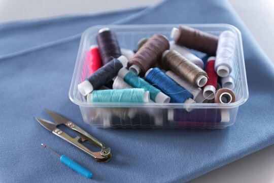 Colorful Thread Spools and Sewing Tools on Blue Fabric