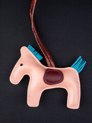 Close up cute leather pink  horse keychain with saddle for bag on black background