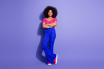 Fashionable young woman in vibrant outfit posing confidently against a purple background with stylish appeal