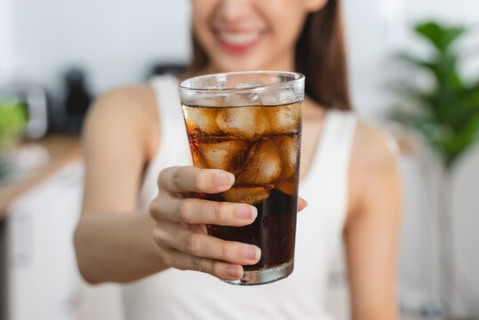person smiling and holding a glass of soft drink soda