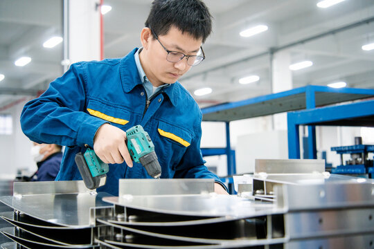 Asian engineer using  using an electric drill in a factory