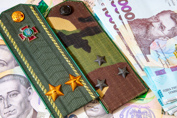Shoulder straps and patches of Ukrainian military on the background of money. War in Ukraine