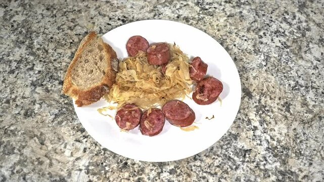 Enjoy a hearty meal featuring tender sausage slices served on a bed of flavorful sauerkraut, showcasing traditional culinary techniques