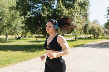A young woman running and training concentrated, while listening to music with headphones, Zaragoza, Spain