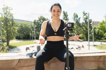 A young woman records herself on video, to explain to her followers, how to perform an exercise and sport workout