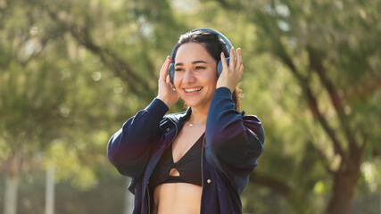 A young woman wearing invisible orthodontic aligners, smiles happily, listening to music with her headphones