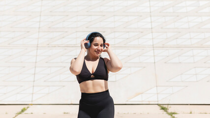 A young woman, dancing and moving, happy, while listening to music with headphones and disconnecting, to relax, after exercising