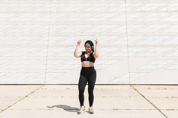 A young woman, dancing and moving, happy, while listening to music with headphones and disconnecting, to relax, after exercising