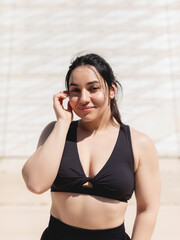 Natural portrait of a young woman with straight black hair, happy, looking at the camera, after a sports and exercise session outdoors