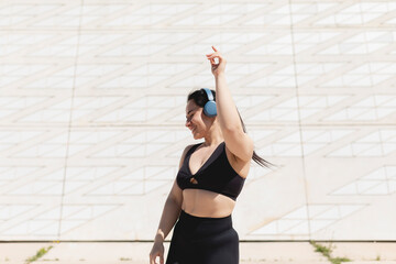 A young woman, dancing and moving, happy, while listening to music with headphones and disconnecting, to relax, after exercising