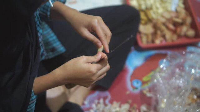 A teenage girl is peeling garlic for cooking spices.