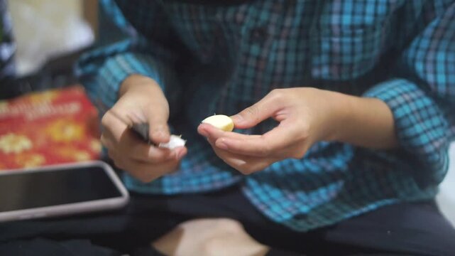 A teenage girl is peeling garlic for cooking spices.