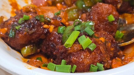 Close up shot of Chinese Manchurian with vegetables.