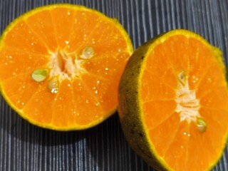 Two oranges are cut in half and placed on a black table