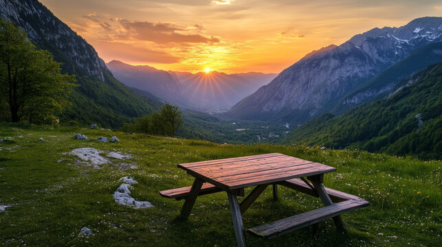 On June 7, 2024, a wooden picnic table offers an incredible sunset view of a valley and mountains along the trail to Savica Waterfall in Slovenia