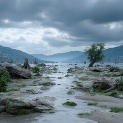 A serene river flows gently through a rocky landscape, reflecting the cloudy sky above as mountains fade into the misty distance on a calm overcast day.