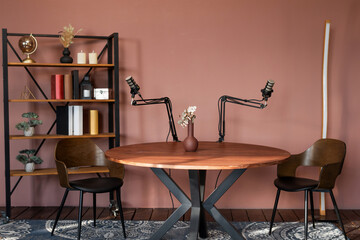 Podcast recording setup featuring a round table with microphones and a stylish shelf in a...