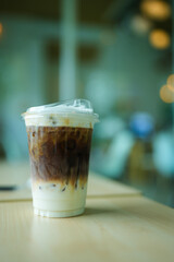 Iced caramel macchiato in plastic cup on wood table.