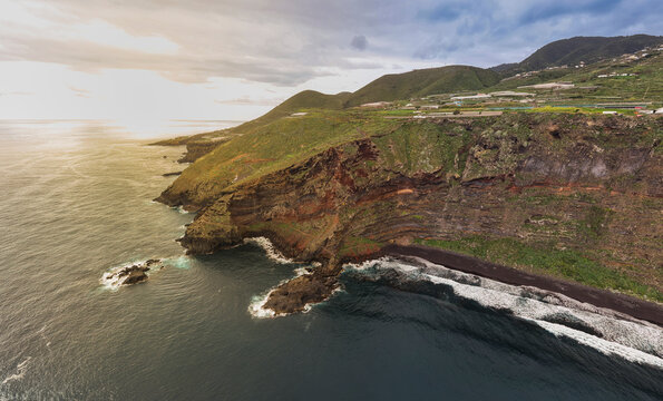 Aerial view of dramatic cliffs and a beautiful banana field at sunset near Nogales Beach, La Palma Island, Canary Islands, Spain.