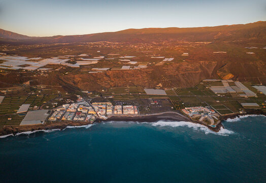 Aerial view of puerto naos town with banana fields and volcanic coastline at sunset, La Palma Island, Canary Islands, Spain.
