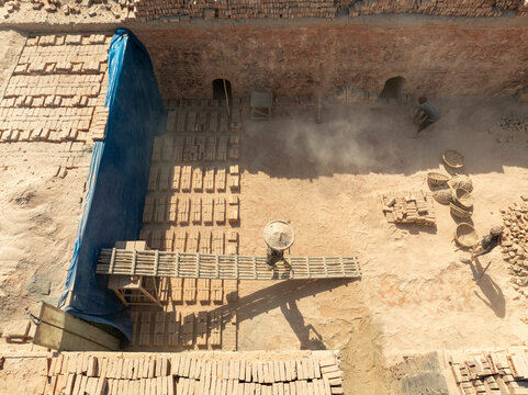 Aerial view of a bustling brick factory with blue tarps and baskets, Suti Para Union, Dhamrai, Dhaka, Bangladesh.