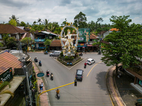 Ubud, Indonesia - 13 November 2022: Aerial view of sculpture Patung Dewa Indra at the crossroads surrounded by urban architecture and tropical greenery, Ubud, Kabupaten Gianyar, Bali, Indonesia.