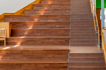 Wooden stadium, stepped seating area with staircase integrated into the seating area in a modern office, school or higher education building.