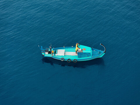 Aerial view of fishermen on a traditional dhoni boat in a serene blue ocean, Vashafaru, Haa Alif, Maldives.