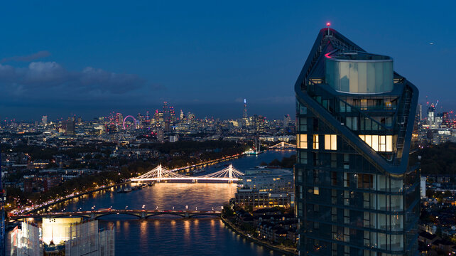 Aerial view of modern cityscape with illuminated skyscrapers and the River Thames at twilight, Hammersmith and Fulham, England, United Kingdom.
