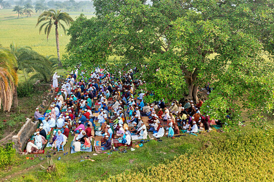 Satkhira, Bangladesh - 11 April 2024: Aerial view of eid prayer gathering in a serene field surrounded by greenery and palm trees, Satkhira, Khulna, Bangladesh.