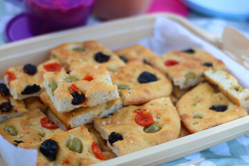 Homemade focaccia with olives and tomatoes, served on a picnic. Selective focus.