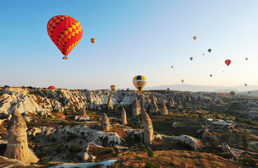 Turkey - 19 May 2025: Aerial view of colorful hot air balloons over unique geological formations in a scenic valley, Cappadocia, Turkey.