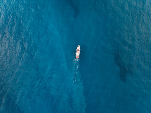 Aerial view of a beautiful yacht sailing on tranquil turquoise waters with scenic coastal landscape, Pissouri, Limassol, Cyprus.
