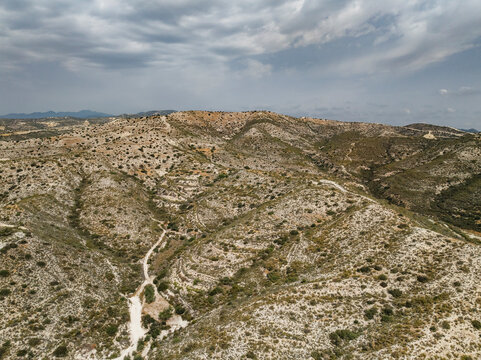Aerial view of rugged Troodos Mountains with scenic hills and a winding path under a cloudy sky, Skarinou, Larnaca, Cyprus.