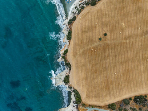 Aerial view of serene haystack field by the tranquil sea and picturesque coastline, Mari, Larnaca, Cyprus.