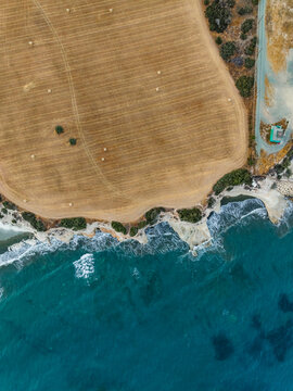 Aerial view of beautiful haystack field by the serene coastline and ocean, Mari, Larnaca, Cyprus.