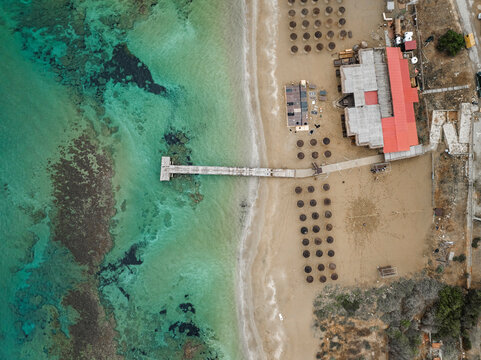 Aerial view of beautiful beach with umbrellas and a pier by the turquoise sea, Agios Sergios, Famagusta, Turkish Republic of Northern Cyprus.