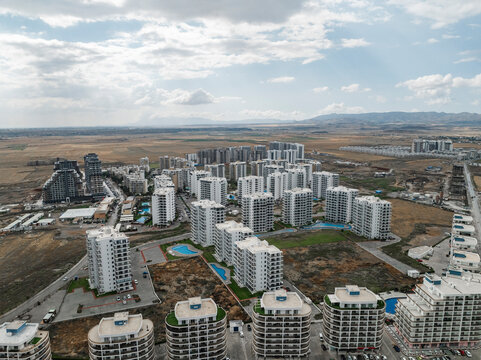 Aerial view of modern cityscape with high-rise buildings and expansive horizon under cloudy sky, Trikomo, Famagusta, Turkish Republic of Northern Cyprus.