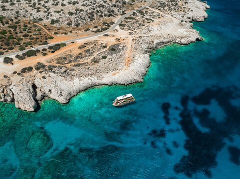 Aerial view of blue lagoon with turquoise water and rugged cliffs, Cape Greco Peninsula, Agia Napa, Famagusta, Cyprus.