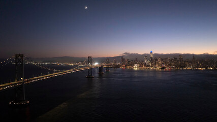 Aerial view of sunset skyline with Golden Gate Bridge and illuminated buildings, Financial District, San Francisco, California, United States.