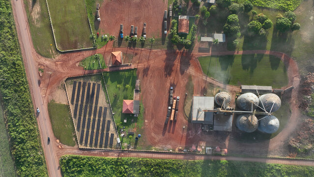 Aerial view of industrial site with silos, fields, and buildings surrounded by greenery and red soil, Santarem, Para, Brazil.