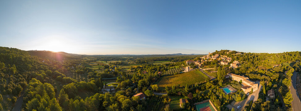 Aerial view of a picturesque village surrounded by tranquil fields and trees at sunset, Moissac-Bellevue, Var, France.
