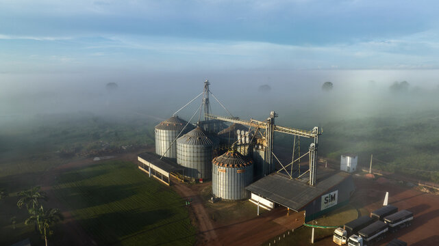 Aerial view of serene agricultural landscape with silos and trees shrouded in morning fog, Santarem, Para, Brazil.