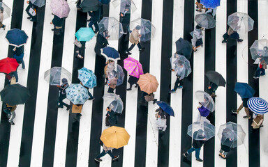 Tokyo City, Japan - 21 March 2021: Aerial view of a crowded junction with pedestrians crossing under umbrellas on a rainy day, Tokyo City, Tokyo Prefecture, Japan.