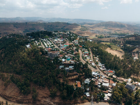 Aerial view of a beautiful rural village with homes and a road nestled in a scenic valley surrounded by mountains and greenery, Debre Birhan, Amhara, Ethiopia.