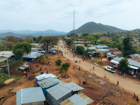 Aerial view of a scenic rural village with traditional houses and a dirt road surrounded by mountains and trees, Kako, Southern Nations Nationalities and Peoples' Region, Ethiopia.