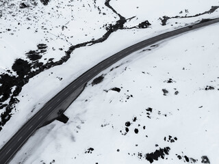 Aerial view of winding snowy road through tranquil alpine mountains, Julierpass, Grisons, Switzerland.